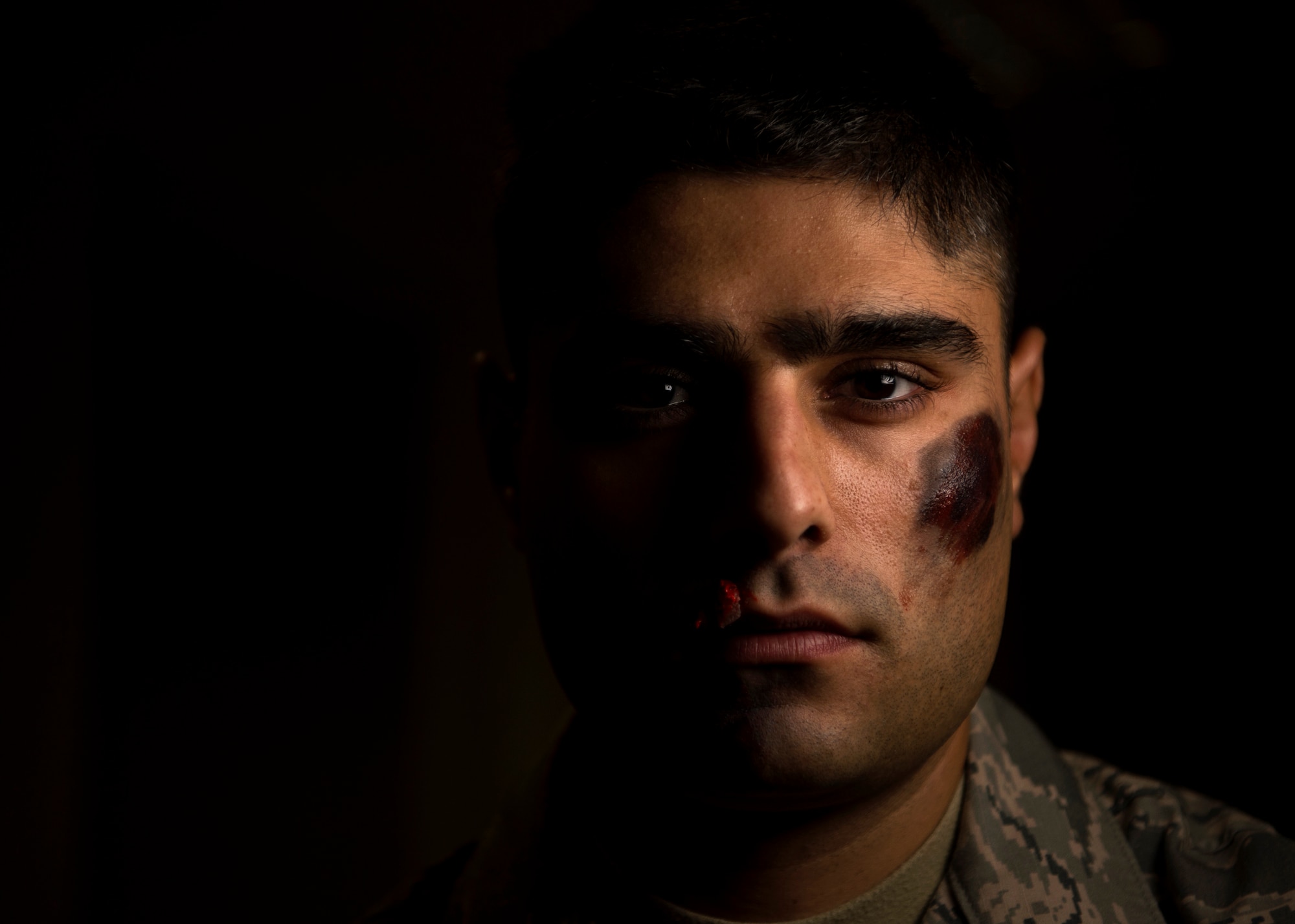 U.S. Air Force Airman 1st Class Roberto Agrusta, 52nd Medical Operations Squadron mental health technician, poses for a portrait while wearing moulage makeup at Spangdahlem Air Base, Germany, Oct. 17, 2018. Agrusta volunteered to simulate a victim of domestic violence for one day in support of the Black Eye Campaign. The social experiment gathered statistics to be used during briefings and education efforts. (U.S. Air Force photo by Airman 1st Class Valerie Seelye)