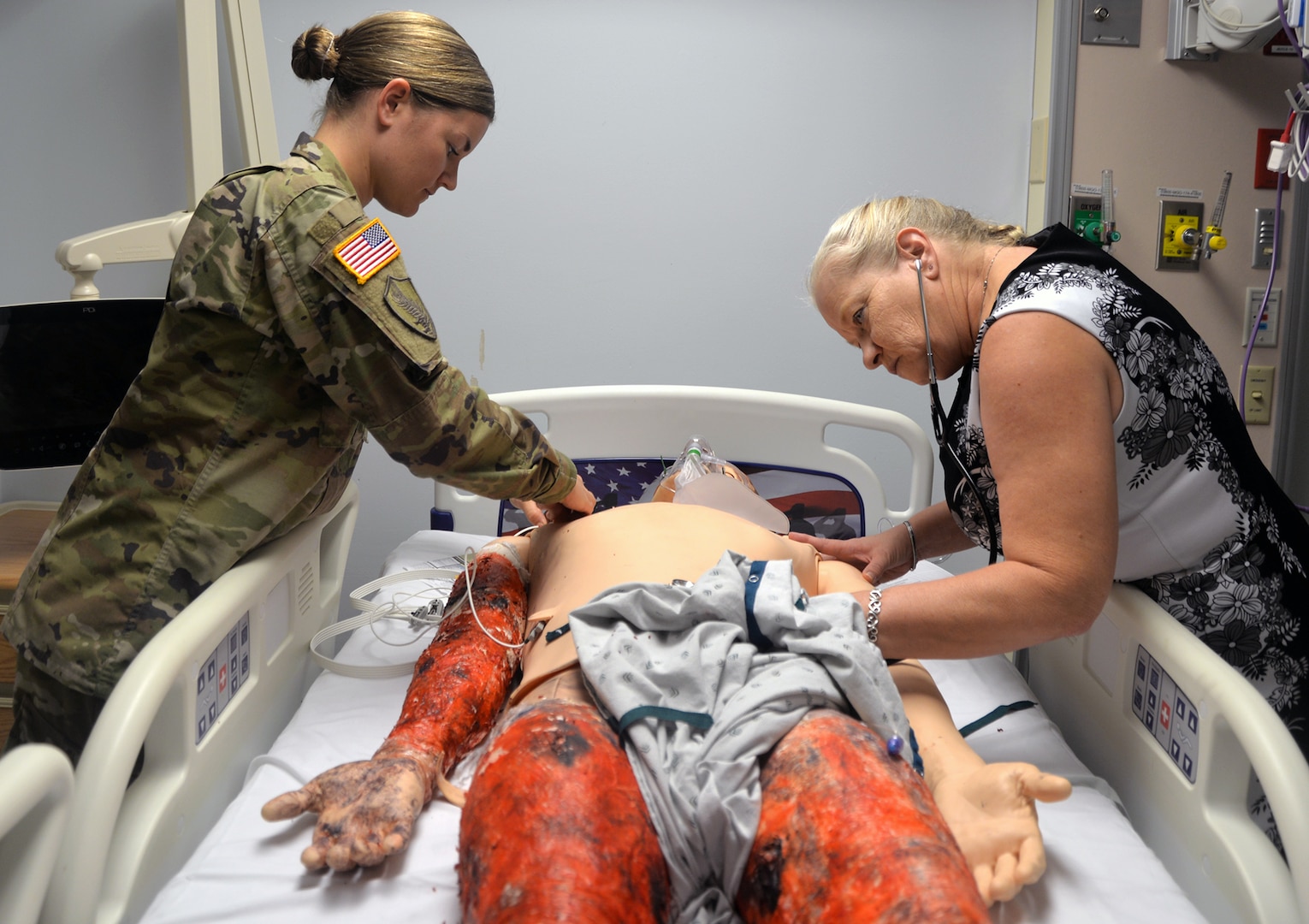 Maj. Allison Ferro, U.S. Army Institute of Surgical Research Burn Center chief of clinical education (left) and Patricia Colston, USAISR Burn Center nurse educator (right) prepare a patient mannequin used for training in the Clinical Pre-Deployment Training Pilot Program. The pilot program gives groups and teams of medical service members who are preparing for deployment the opportunity to train at the USAISR Burn Center, which is the sole facility within the Department of Defense that cares and treats burn patients who are active-duty and injured in combat, military dependents and non-military civilian emergencies.