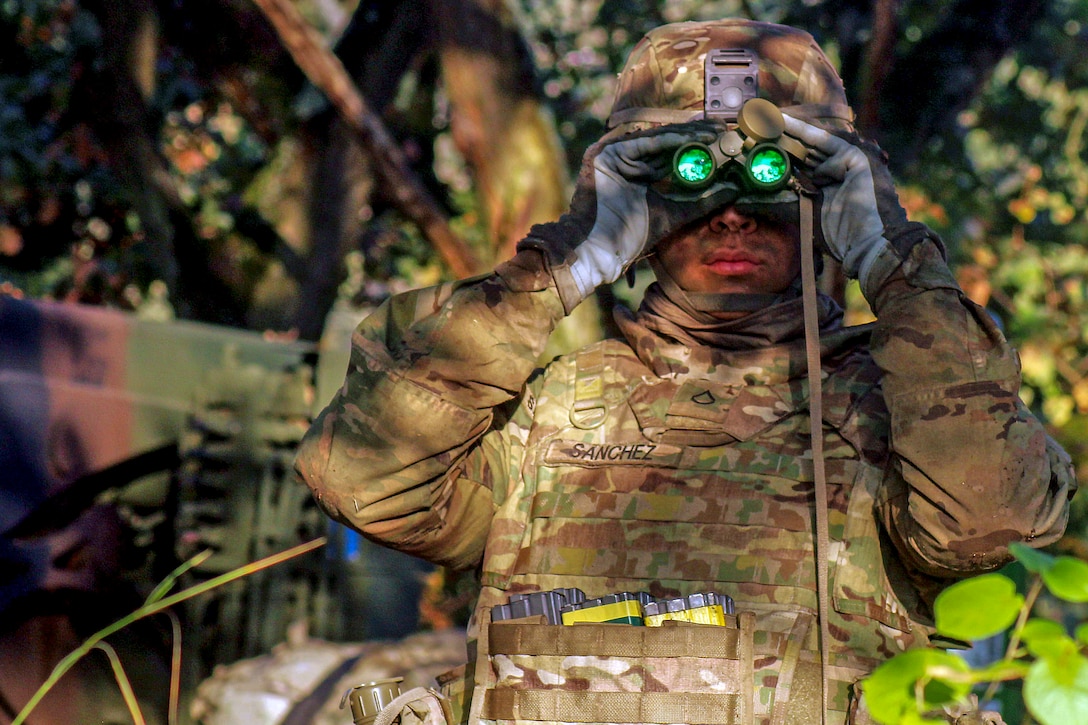 A soldier looks through binoculars.