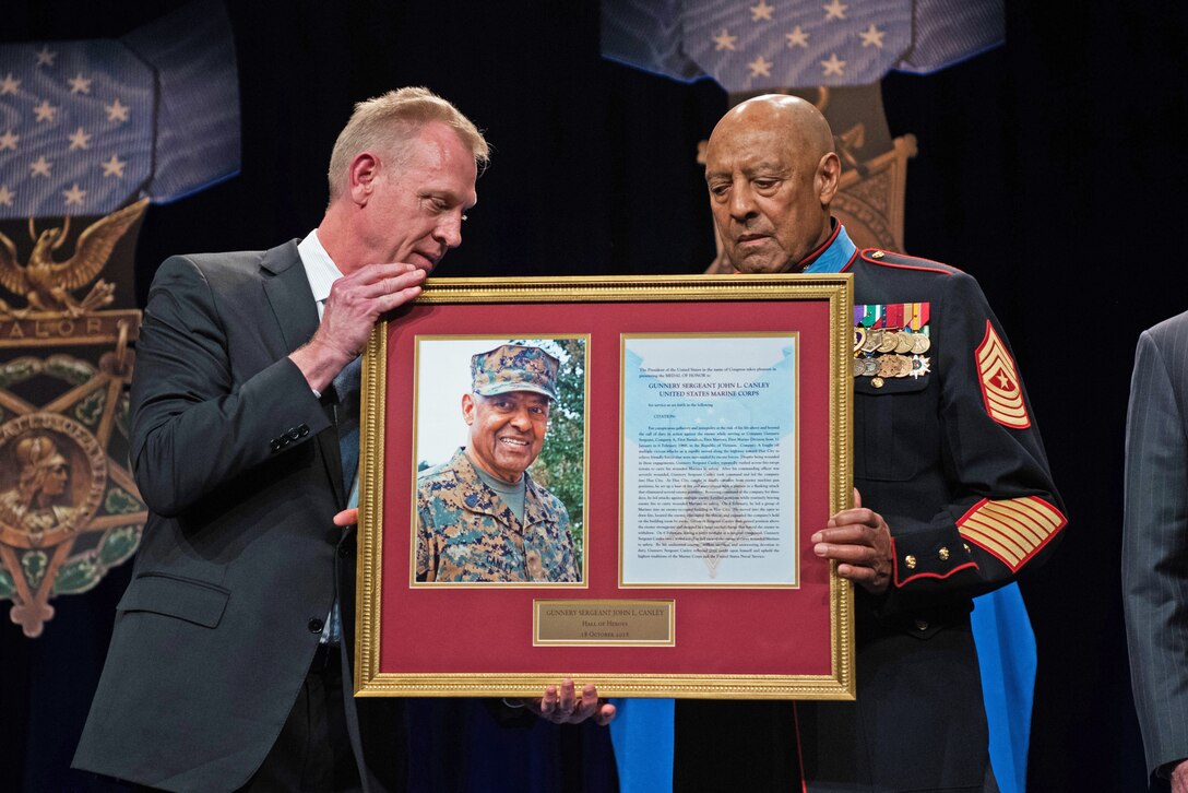 Deputy Defense Secretary Patrick M. Shanahan holds a photo frame with Medal of Honor recipient retired Marine Corps Sgt. Maj. John L. Canley.