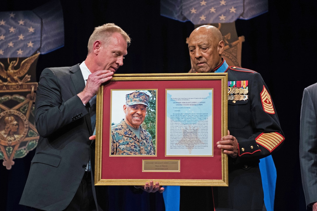Deputy Defense Secretary Patrick M. Shanahan holds a photo frame with Medal of Honor recipient retired Marine Corps Sgt. Maj. John L. Canley.