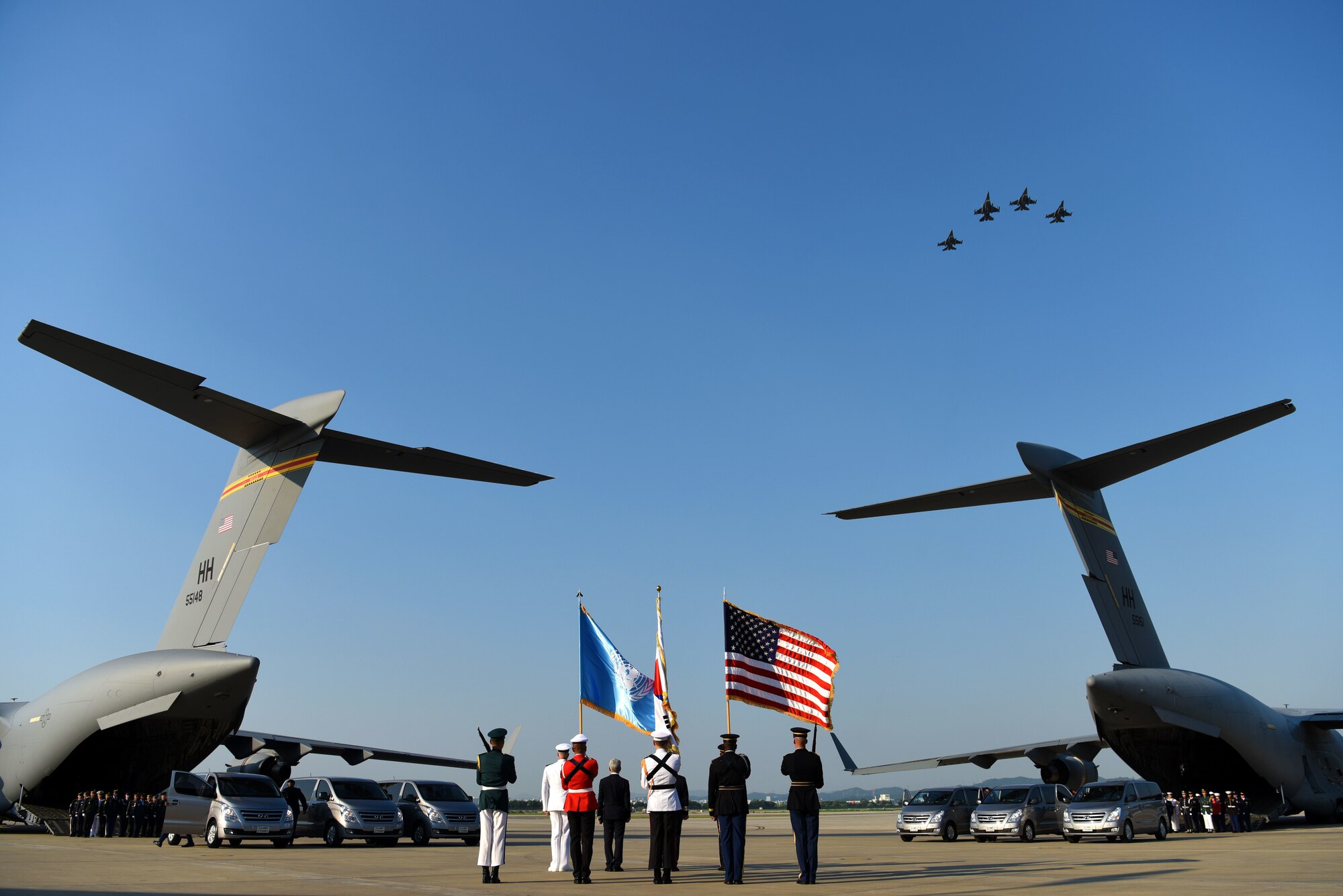 The United Nations Command Honor Guard prepares to transfer caskets of remains onto waiting C-17 Globemaster IIIs as members of the 36th Fighter Squadron perform a missing man flyover at Osan Air Base, Republic of Korea, Aug. 1, 2018. Two C-17s left Osan AB for Joint Base Pearl Harbor-Hickam, Hawaii, where members of the Defense POW/MIA Accounting Agency will attempt to identify the remains of the fallen heroes. The UNC repatriated 55 cases of remains from the Democratic People’s Republic of Korea. (U.S. Air Force photo by Senior Airman Kelsey Tucker)