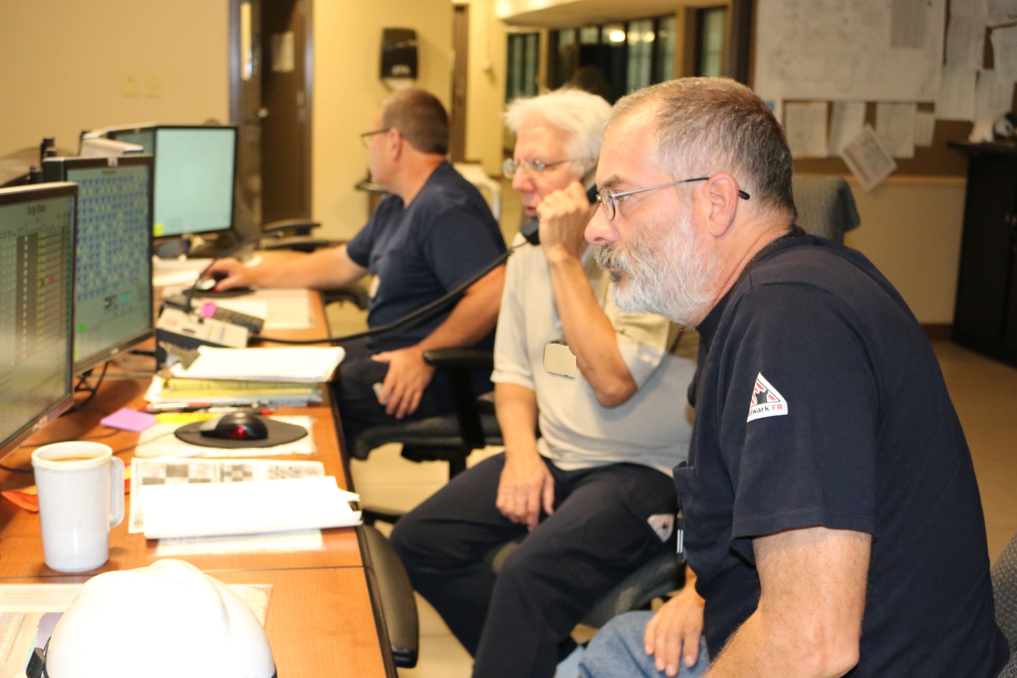 AEDC electricians Carlos Bussche, at right, Chuck Kurtsinger, center, and Eddie Lee, left, check the plant control valves from a control room in the von Kármán Facility at Arnold Air Force Base. (U.S. Air Force photo by Bradley Hicks) (This image was manipulated by obscuring badges for security purposes)