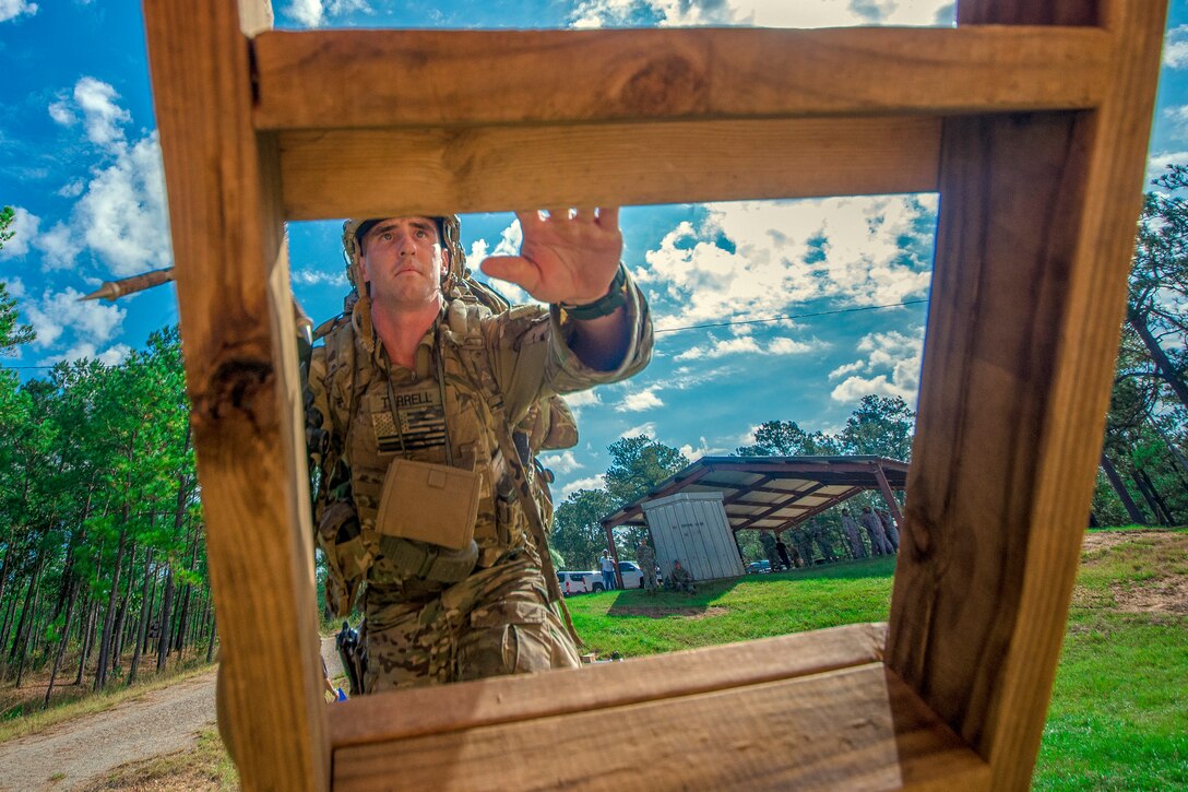 A soldier climbs a wooden obstacle.