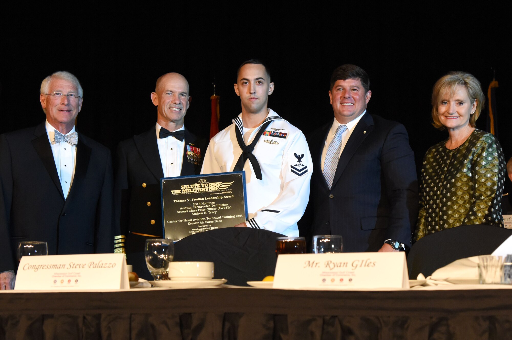 U.S. Navy Aviation Electronics Technician 2nd Class Andrew Tracy, Center for Naval Aviation Technical Training Unit Keesler instructor, receives the Thomas V. Fredian Community Leadership Award from members of the head table during the 40th Annual Salute to the Military inside the Mississippi Coast Convention Center, in Biloxi, Mississippi, Oct. 16, 2018. The Salute to the Military event recognized the men and women who serve in the military along the Gulf Coast. (U.S. Air Force photo by Kemberly Groue)