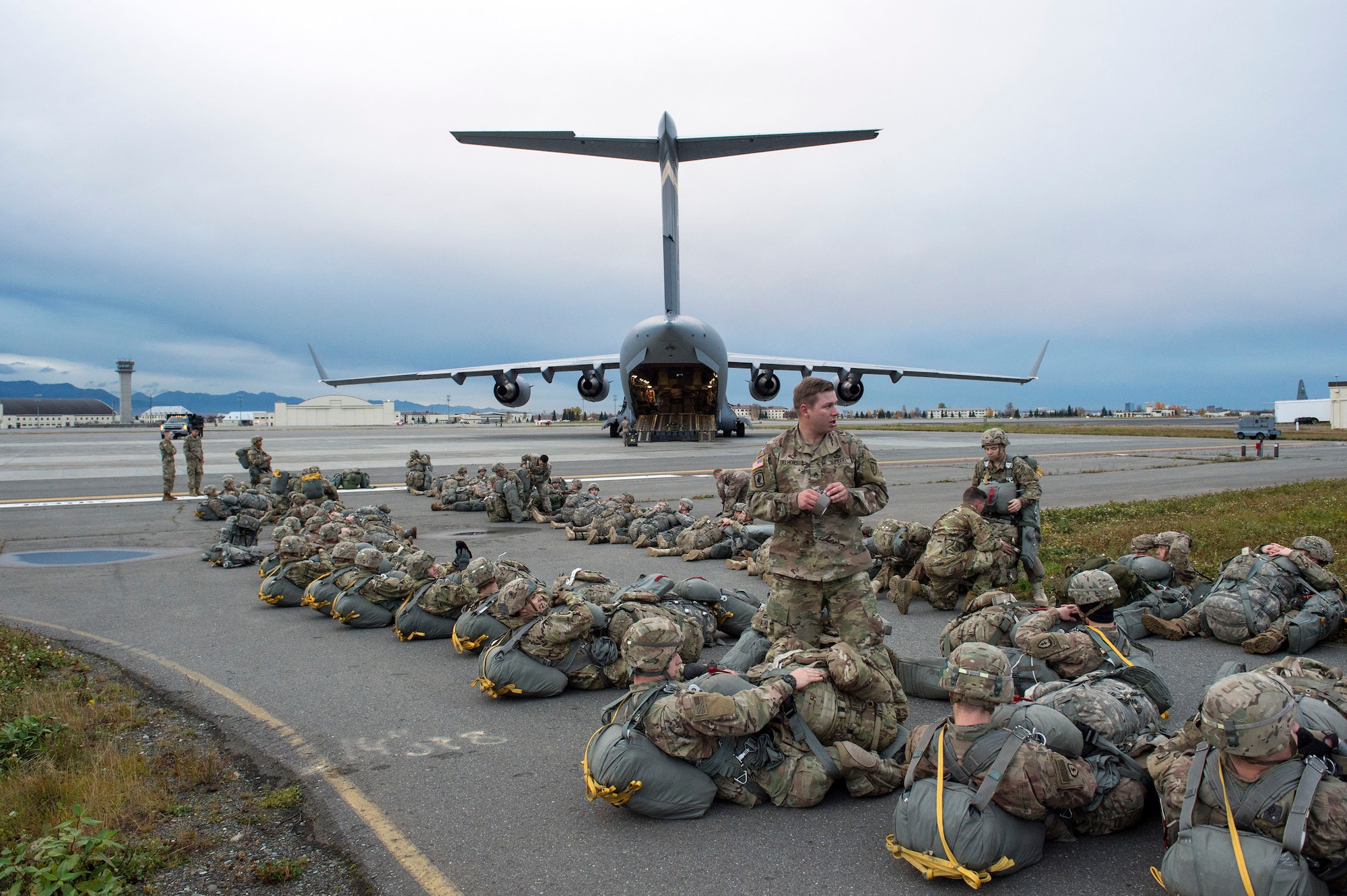 Army paratroopers from the 4th Infantry Brigade Combat Team (Airborne), 25th Infantry Division, U.S. Army Alaska, wait to board an Air Force C-17 Globemaster III, assigned to the 535th Airlift Squadron, out of Joint Base Pearl Harbor-Hickam, Hawaii, while participating in Arctic Anvil 19-01, at Joint Base Elmendorf-Richardson, Alaska, Oct. 9, 2018.