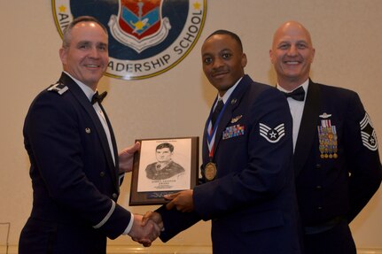Col. Mark Harris, left, 437th Maintenance Group commander, and
Chief Master Sgt. Kenneth Rossa, right, 437th Maintenance Group superintendent, present Staff Sgt. Trae Williams, 437th Operational Support Squadron, a plaque for earning the John L. Levitow Award during the class 18-G Airman Leadership School graduation at the Charleston Club here Oct. 18, 2018. The Levitow Award is the highest honor awarded to an ALS graduate and is given to the Airman who displays the highest level of leadership qualities during the course. ALS is a five-week course encompassing lessons in the principles of supervision and management, the importance of communication and military professionalism.
