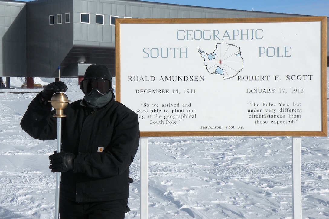 Airman poses in front of South Pole.