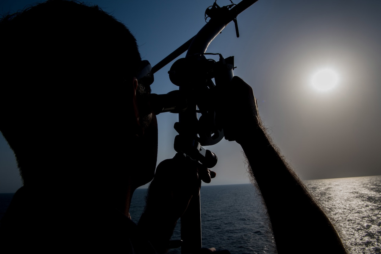 Sailor uses navigational sextant.