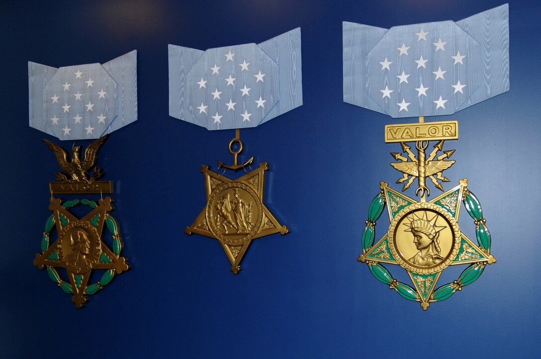 Three large recreations of Medals of Honor are displayed on a blue wall.