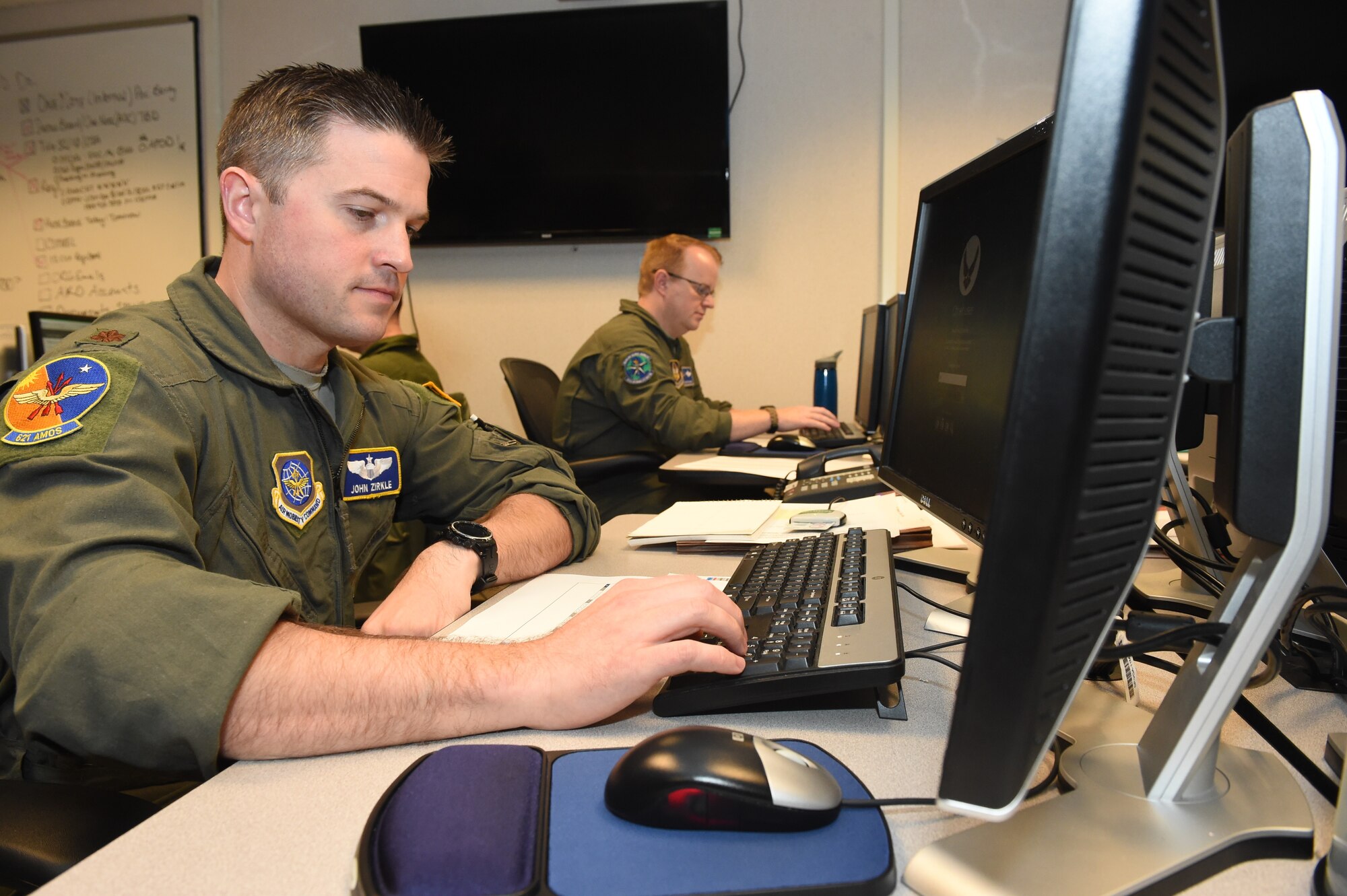Two U.S. Air Force Airmen log into computers using keyboards inside an Air Operations Weapon System Suite at Joint Base McGuire-Dix-Lakehurst, October 12.