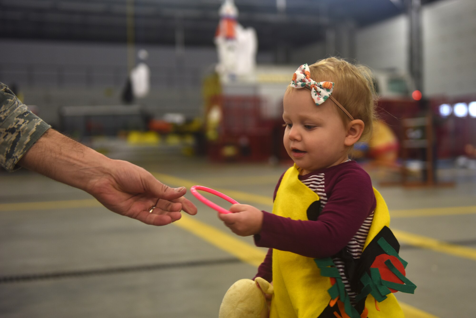 The daughter of a deployed Team Mildenhall Airman takes hold of a ring from U.S. Air Force Lt. Col. Joshua Lundeby, 100th Operations Support Squadron commander, during a Halloween-themed Hearts Apart event Oct. 18, 2018, on RAF Mildenhall, England. The event was hosted by the 100th Civil Engineering Squadron along with the Mildenhall Key Spouses’ Club. The families enjoyed food, games and a costume contest. (U.S. Air Force photo by Airman 1st Class Brandon Esau)