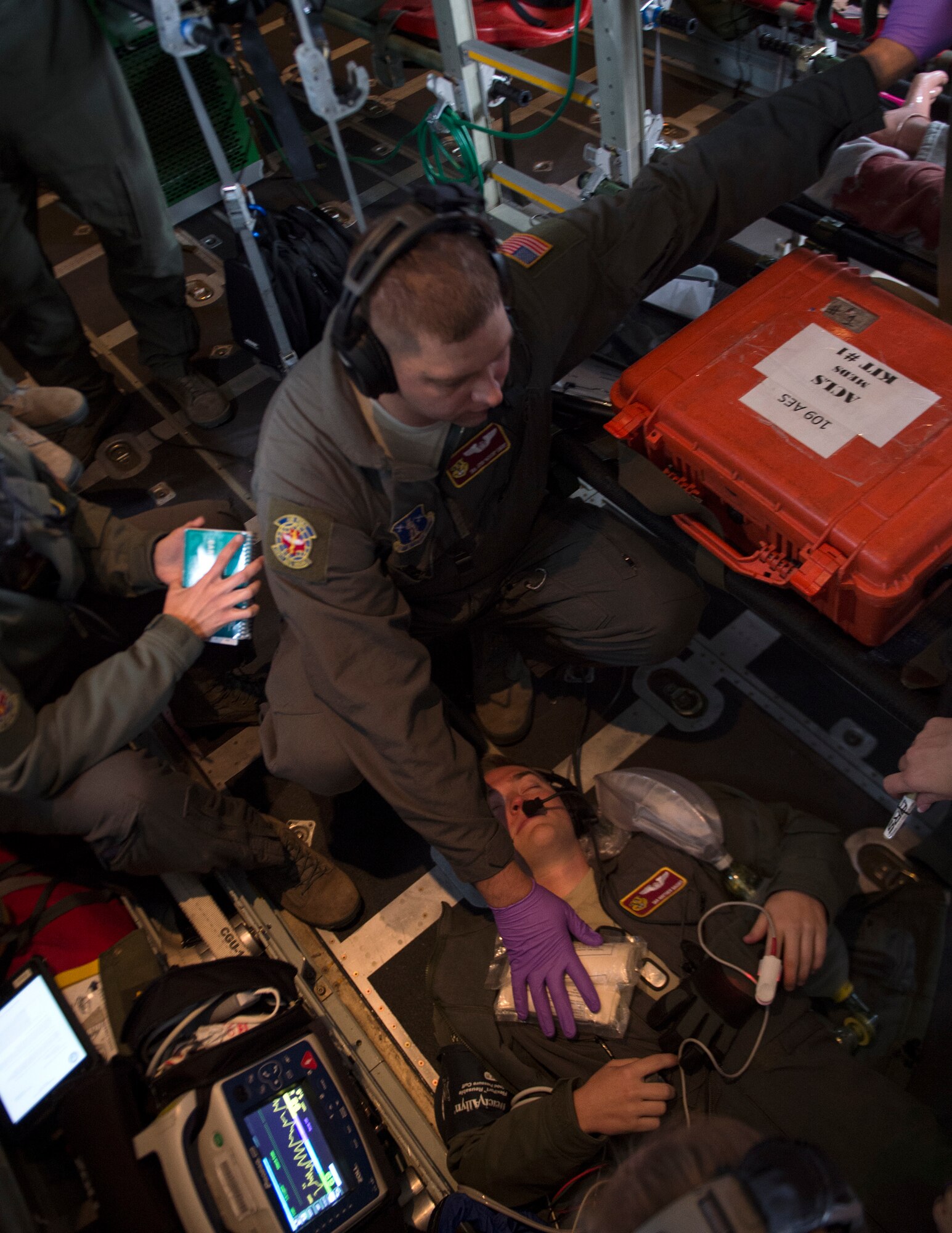 U.S. Air Force Senior Airman Joshua Ewert, center, 109th Aeromedical Evacuation Squadron, places bandages onto a role-player simulate injuries during a training flight in Minn., Oct. 9, 2018.