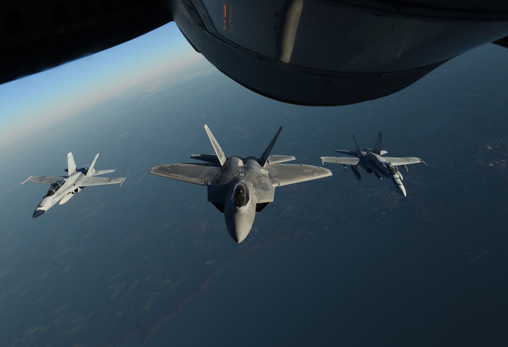 A U.S. Air Force F-22 Raptor and two Finnish air force F/A-18 Hornets fly behind a U.S. Air Force KC-135 Stratotanker during training off the coast of Finland, Oct 19, 2018. The Raptors trained with different NATO allies and partners to deter any potential threats and increase regional security. (U.S. Air Force photo by Senior Airman Luke Milano)