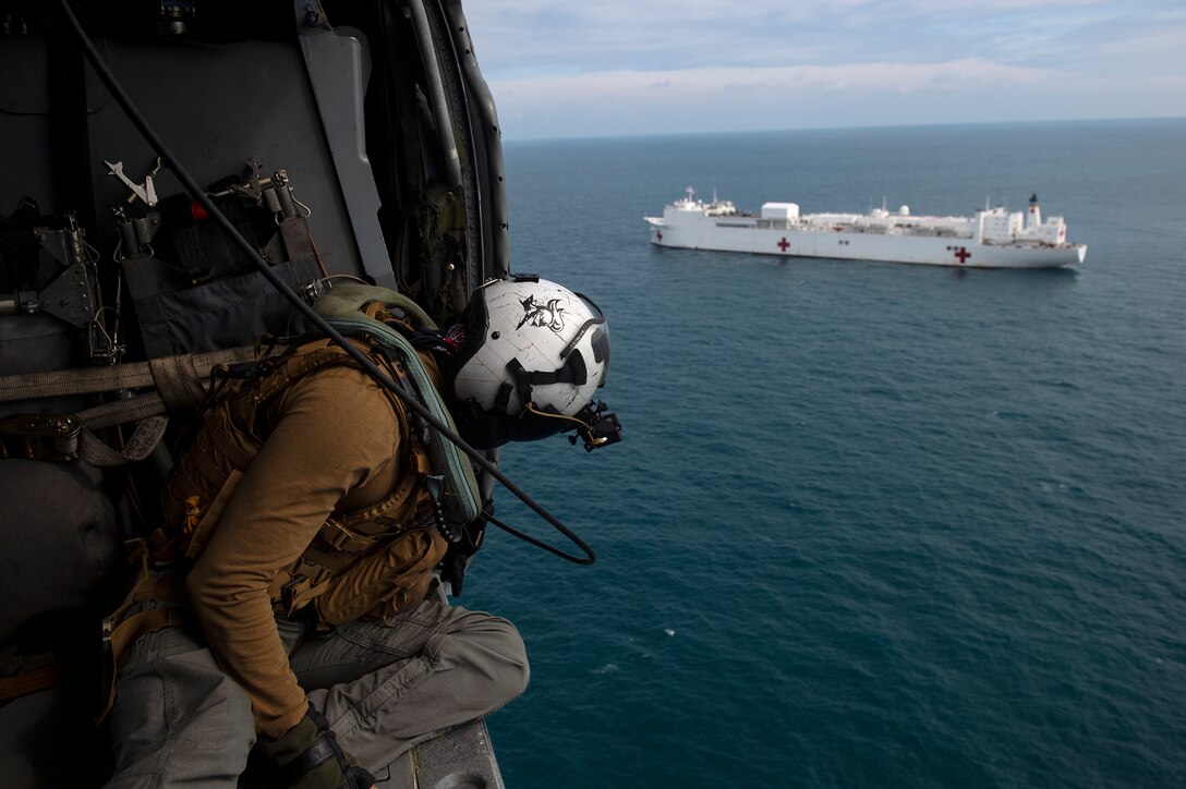 U.S. Navy aircrew on a MH-60S Seahawk ensures the helicopter remains clear during a vertical replenishment with USNS Comfort.
