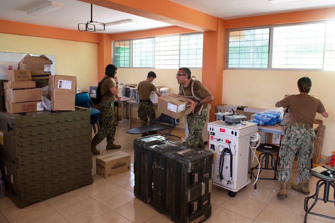 Sailors move medical supplies from the hospital ship USNS Comfort (T-AH 20) onto one of two medical sites in preparation for upcoming treatment days.