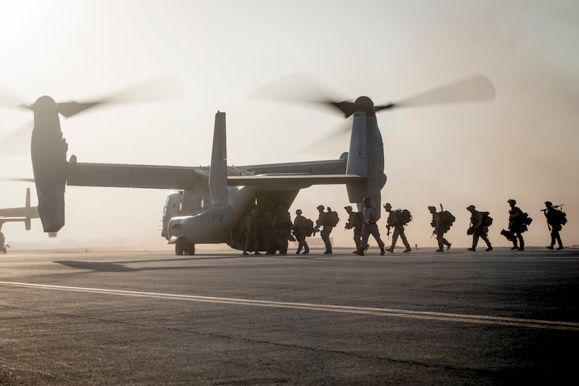 Marines board an Osprey in a line.