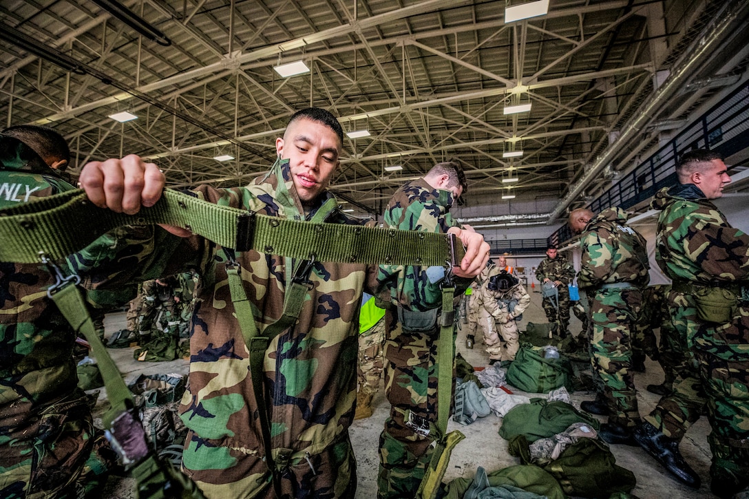 An airman adjusts straps on his gear.