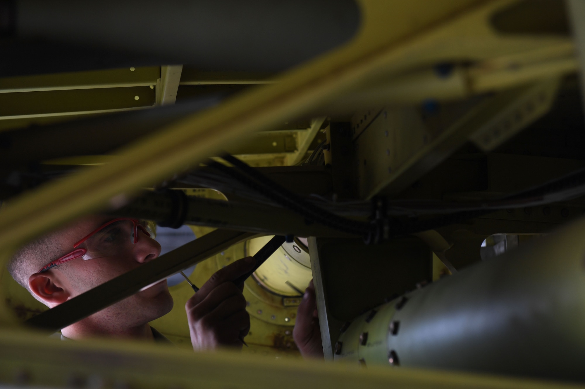 A man uses a screwdriver on an aircraft.