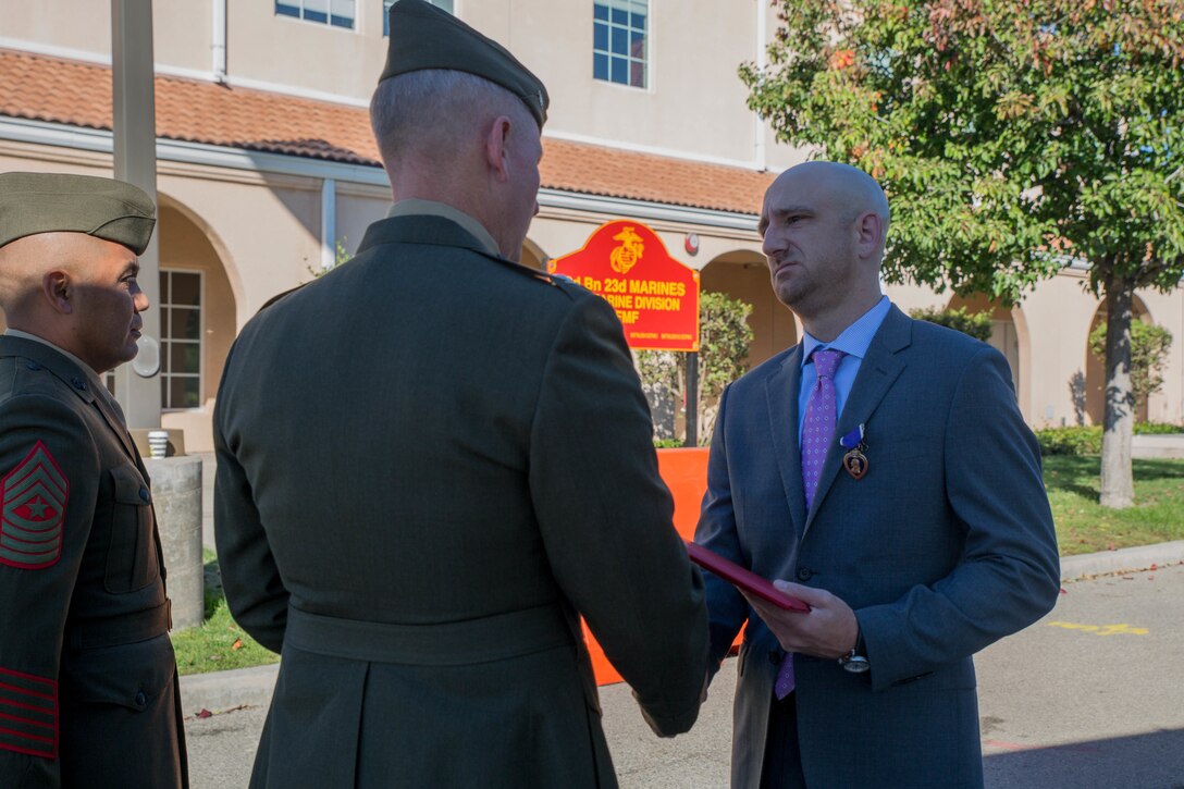 Marine veteran Matthew R. Follett (right), is presented with the Purple Heart by Col. Justin J. Anderson, battalion Inspector Instructor for 2nd Battalion, 23rd Marine Regiment, 4th Marine Division (center) and Sgt. Maj. Israel Rivera, battalion sergeant major of 2nd Bn., 23rd Marines, 4th MarDiv (left) in Pasadena, Calif. on October 19, 2018. SSgt Follett received the award for injuries sustained while serving as an active duty counter intelligence specialist with 3rd Battalion, 4th Marine Regiment, 1st Marine Division, on January 7, 2010. (U.S.  Marine Corps photo by Lance Cpl. Samantha Schwoch/released)