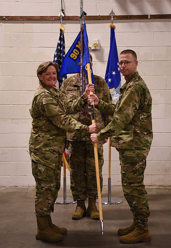 Col. Tricia Van Den Top, 90th Mission Support Group commander, passes the guidon to Lt. Col. Brian Low, 90th Civil Engineering Squadron commander, during the 90 CES assumption of command ceremony at F.E. Warren Air Force Base, Wyo., Oct. 22, 2018, The ceremony signified the assumption of command and formal transfer of authority to Low.