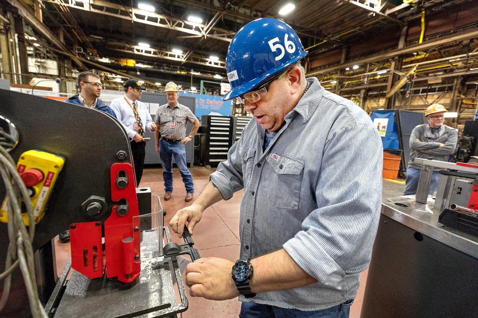 Jeff Pugh, a pipefitter, uses a new 3D-printed alignment tool to help punch holes in an iron pipe hanger.