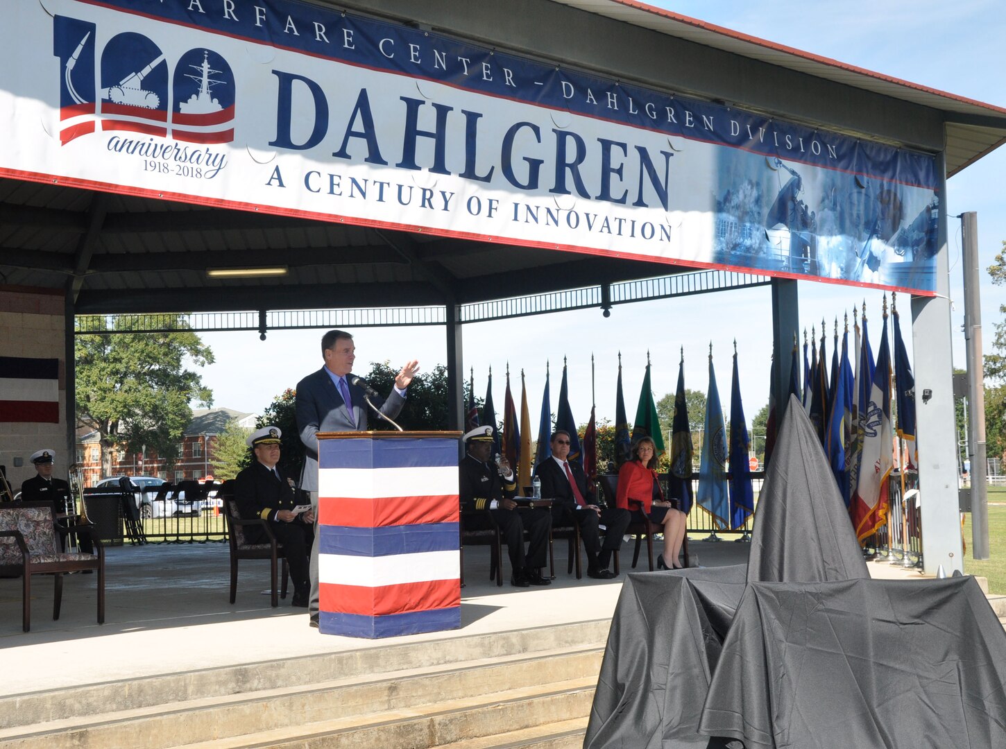 IMAGE: DAHLGREN, Va. (Oct. 19, 2018) – U.S. Senator Mark Warner lists a series of Dahlgren achievements from World War II long guns to global positioning system technology while speaking to the military and civilian audience gathered to celebrate the NSWCDD centennial. “This is an installation where a great deal of innovation and collaboration take place,” said Warner. “We’re going to need that same level of collaboration, cutting edge experimentation as we move forward for the next 100 years, not only to protect our country but to make sure that we’re able to match the innovation and have the kind of protections that will keep this nation strong, safe and free. So, for all you’ve done for the last 100 years, I say thank you.”