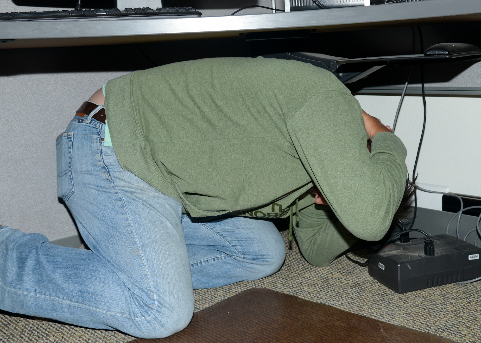 A member of Team Edwards ducks and covers during the Great ShakeOut earthquake exercise drill Oct. 18. According to the American Red Cross, drop, cover, and holding under a table or desk is still the best recommendation while indoors during an earthquake. (U.S. Air Force photo by Giancarlo Casem)