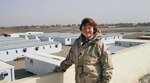 Becky stands on a rooftop overlooking small buildings in a desert town