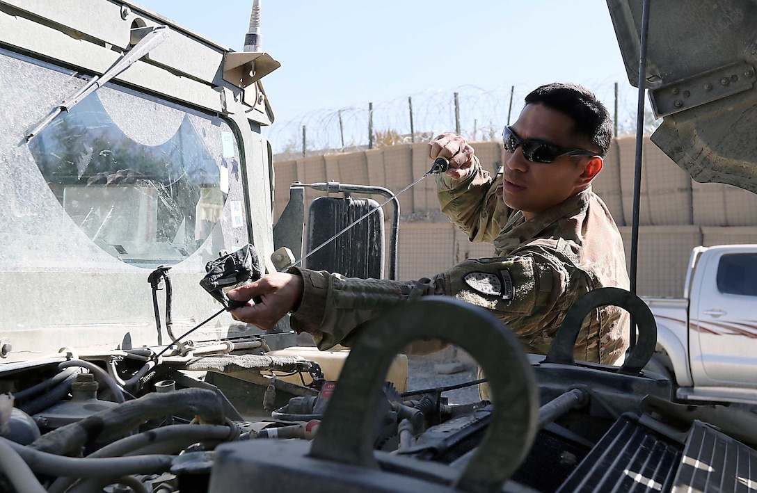 Sgt. Roque Torres, 1st Security Force Assistance Brigade, checks the oil on an Afghan Humvee as part of a training video being produced at Forward Operating Base Lightning, Afghanistan, Oct. 12.
Torres and two other soldiers from the 1st Security Force Assistance Brigade headquarters are training the Afghan National Defense and Security Forces (Army and Police) in an innovative way to conduct preventive maintenance on vehicles.
Using the video recording capability from either a laptop computer or smart phone, these Soldiers ultimately end up with a training video showing Afghans exactly what they need to do to keep vehicles maintained. (Photo by Jon Micheal Connor, Army Public Affairs)