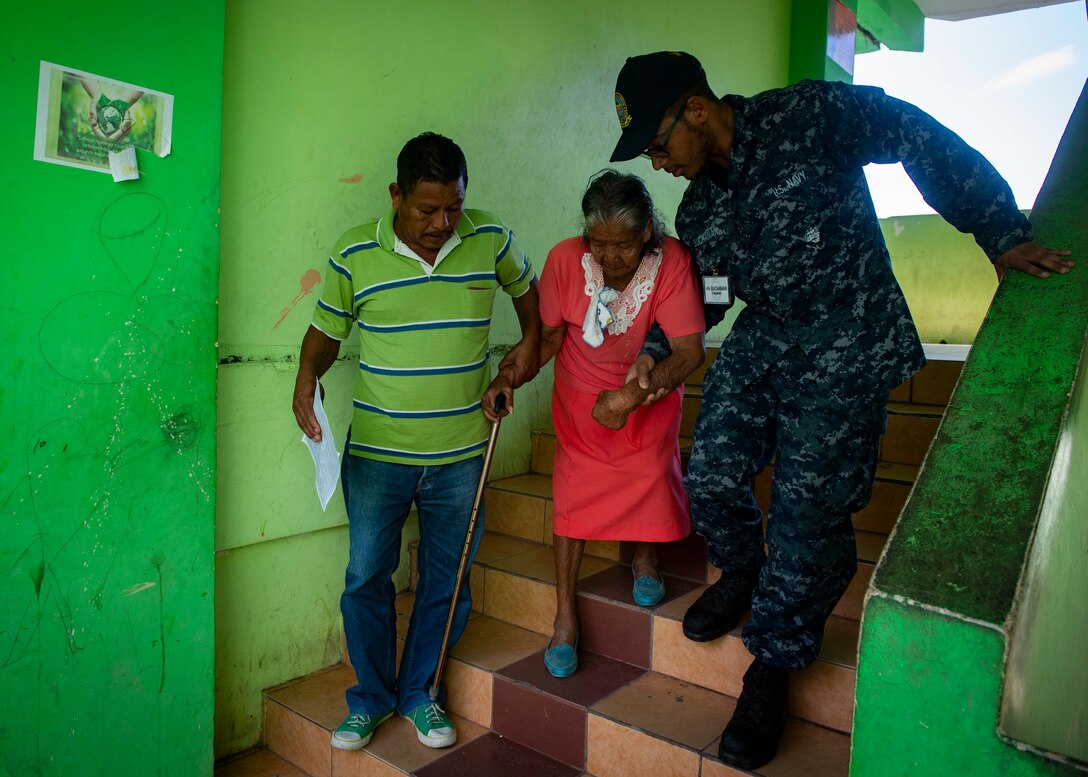 A U.S. Navy Hospitalman helps a patient down the stairs.