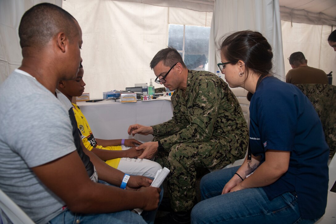 A Navy doctor and an Ecuadorian medical student examine a patient in Ecuador.