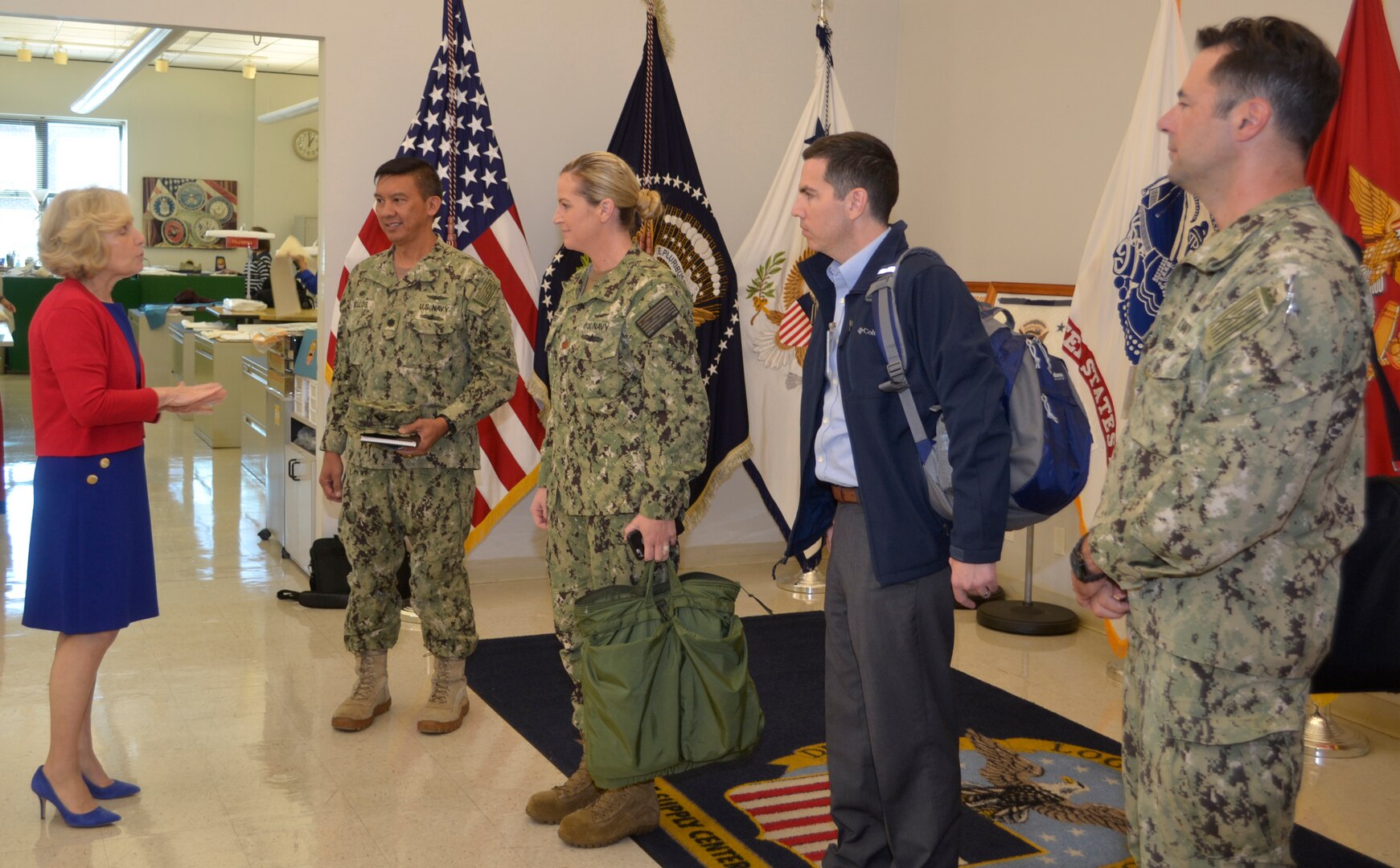 DLA Aviation Industrial Support Activities commanders listen as Linda Farrell, DLA Troop Support’s Flag Room supervisor, welcomes the visitors with a brief history of DLA’s hand embroidery specialists in Philadelphia Oct. 18, 2018.