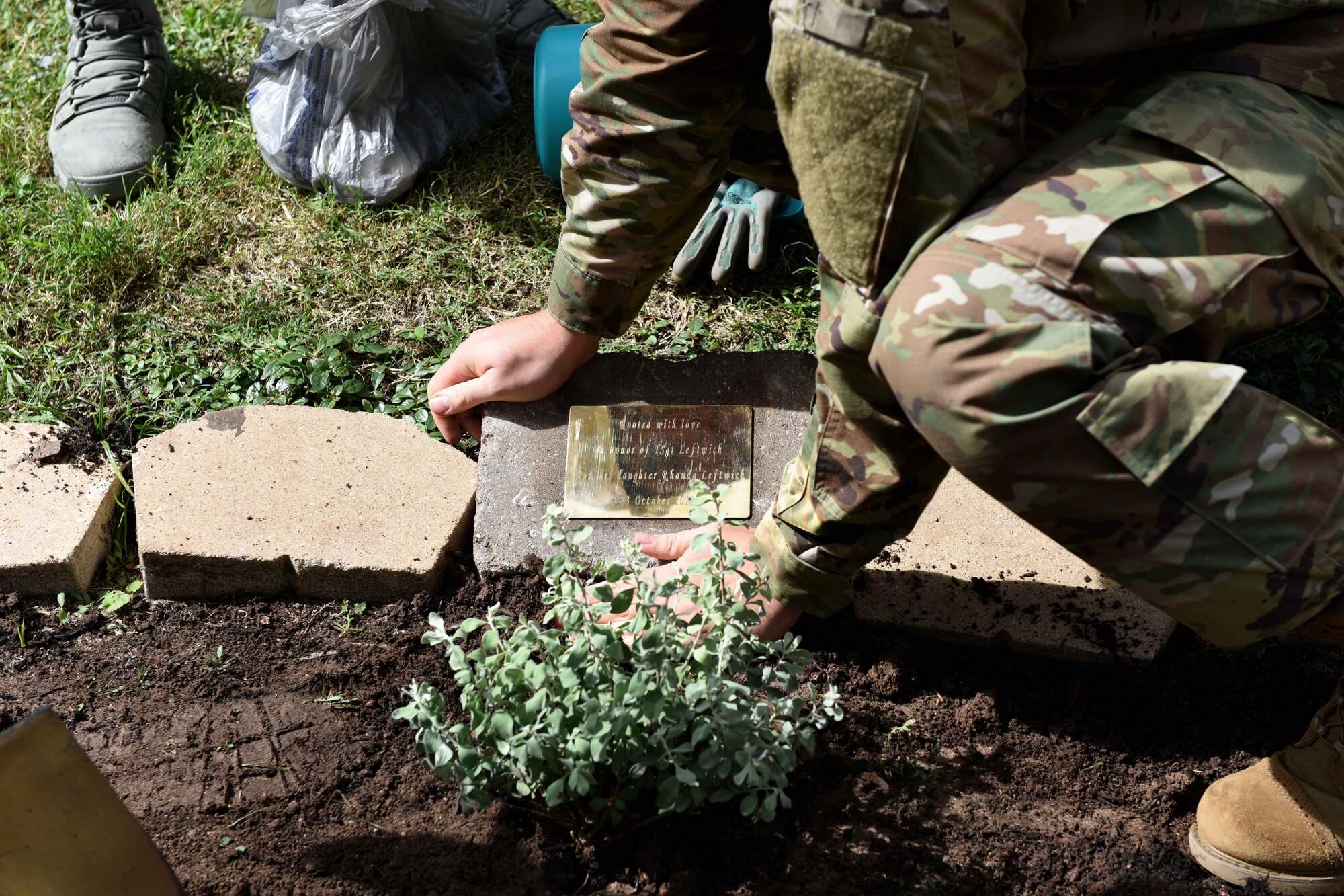 U.S. Air Force Staff Sgt. Dillon Duermyer, 17th Medical Support Squadron medical records NCO in charge, lays a memorial plaque near Leftwich Hall on Goodfellow Air Force Base, Texas, Oct. 23, 2018. Goodfellow dedicated a pavilion along the troop walk as a second memorial to Tech. Sgt. Raymond Leftwich. (U.S. Air Force photo by Senior Airman Randall Moose/Released)