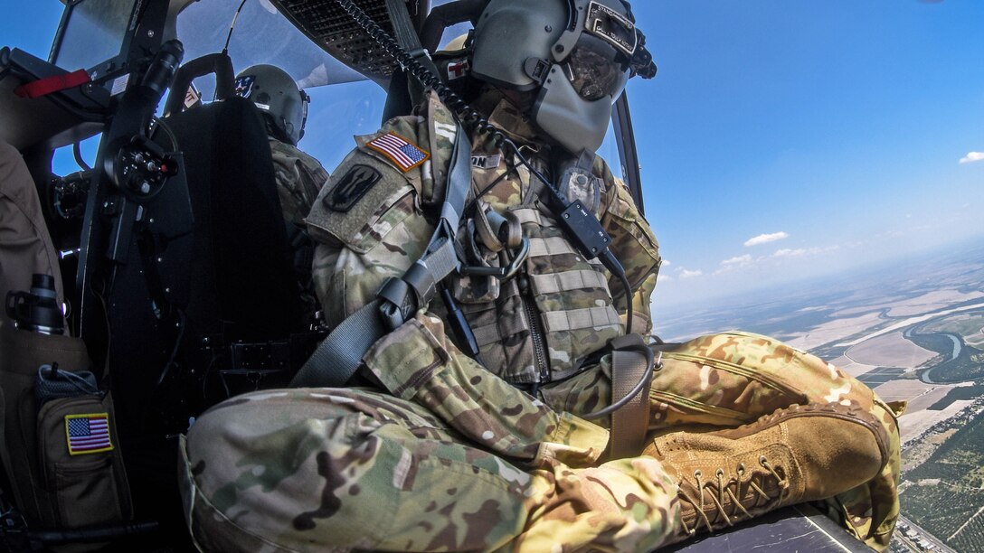 Guardsmen in an aircraft fly over an area near the southern border.