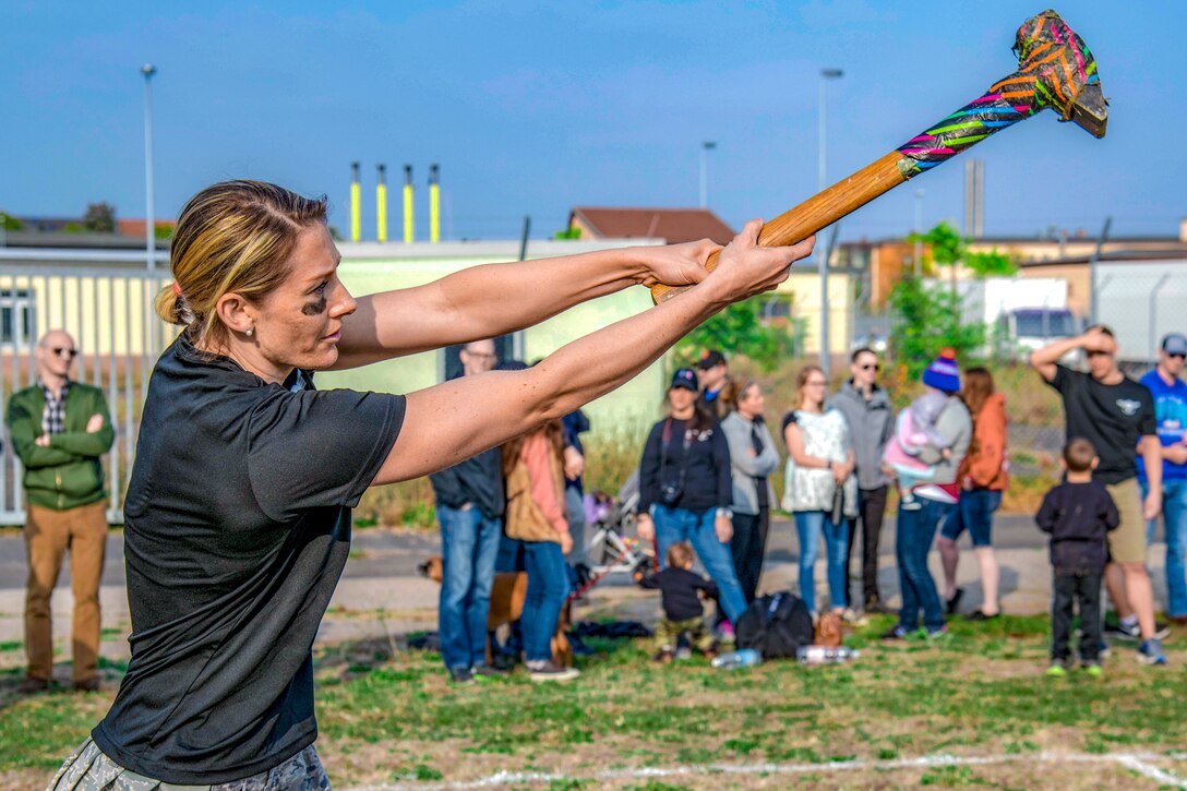 A woman wearing face paint swings a giant hammer.