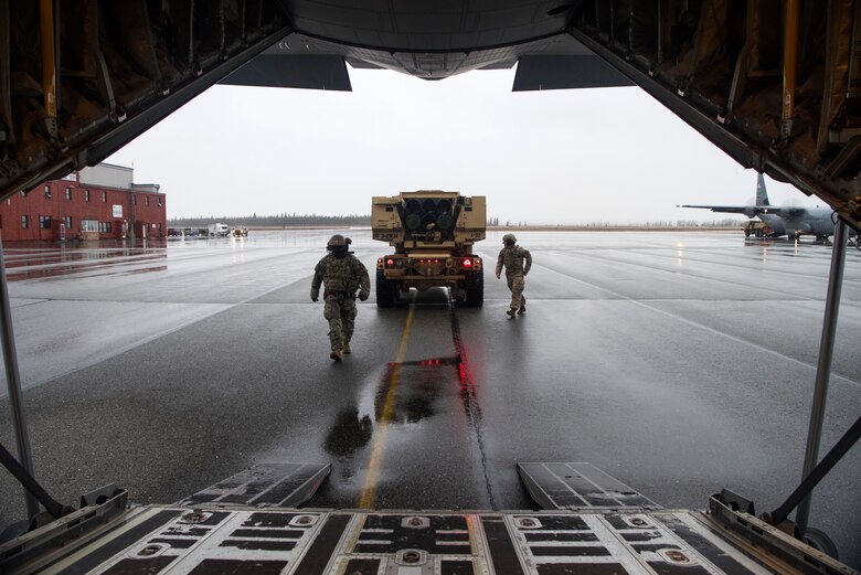 U.S. Army Staff Sgt. Shane Woods, a High Mobility Artillery Rocket System (HIMARS) chief and U.S. Army Sgt. Jay Bryant, a HIMARS gunner, both assigned to Alpha Battery, 3rd Battalion, 27th Field Artillery Regiment (HIMARS), 18th Field Artillery Brigade, Fort Bragg, N.C., prepare to board a U.S. Air Force C-130J Super Hercules at Fort Greely, Alaska, Oct. 19, 2018, during Red Flag-Alaska 19-1. Their unit was tasked to provide long-range artillery support during RF-A, allowing the unit to showcase its capabilities and develop relationships with other services. Transporting the M142 HIMARS in a U.S. Air Force C-130J Super Hercules requires deflating the tires and lowering the suspension.
