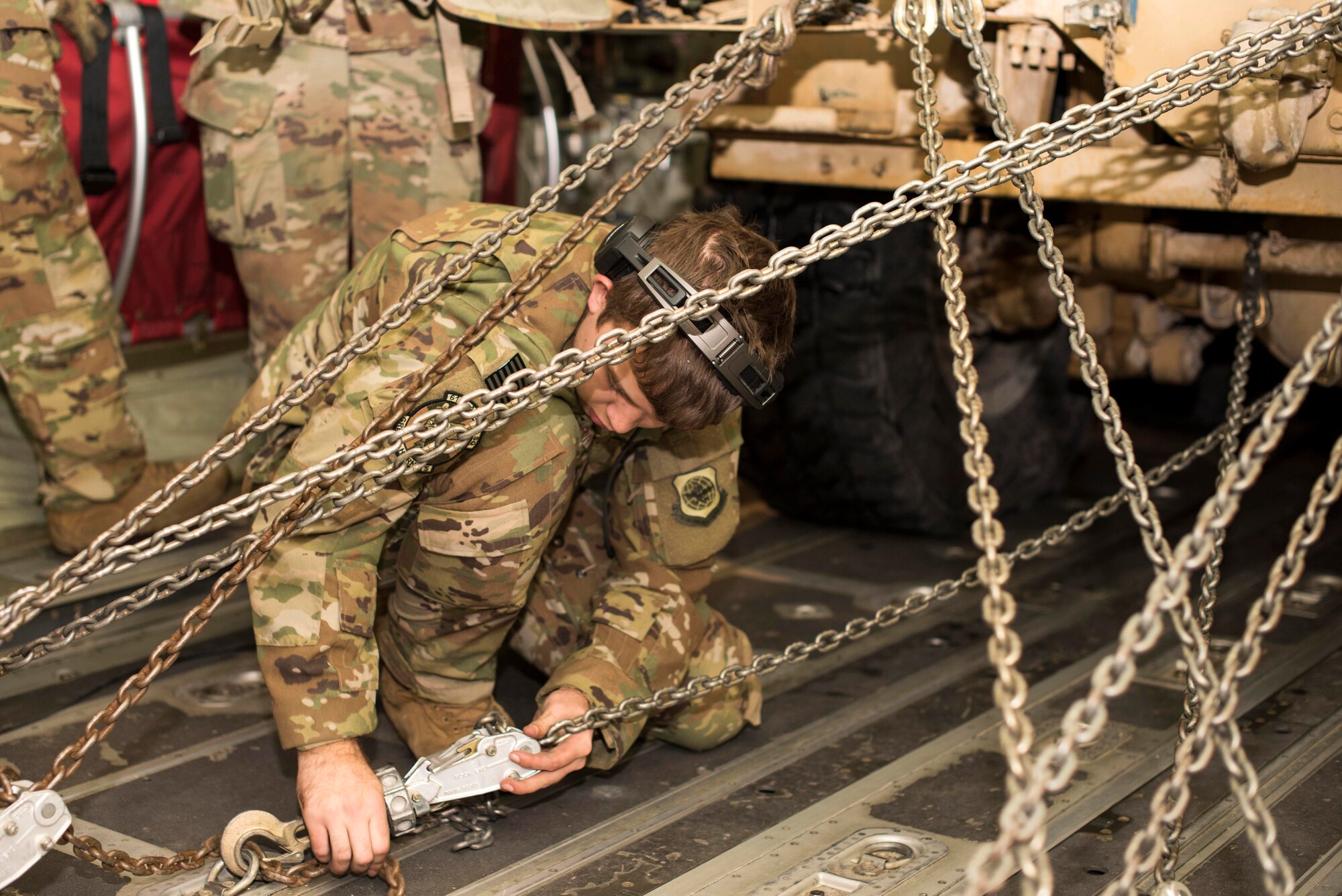 U.S. Air Force Airman 1st Class William Kern, 61st Airlift Squadron loadmaster assigned to Little Rock Air Force Base, Ark., secures chains on a M142 High Mobility Artillery Rocket System (HIMARS) inside a U.S. Air Force C-130J Super Hercules at Fort Greely, Alaska, Oct. 19, 2018, during Red Flag-Alaska 19-1. The M142 HIMARS was restrained with chains both in front and back to prevent it moving during flight.
