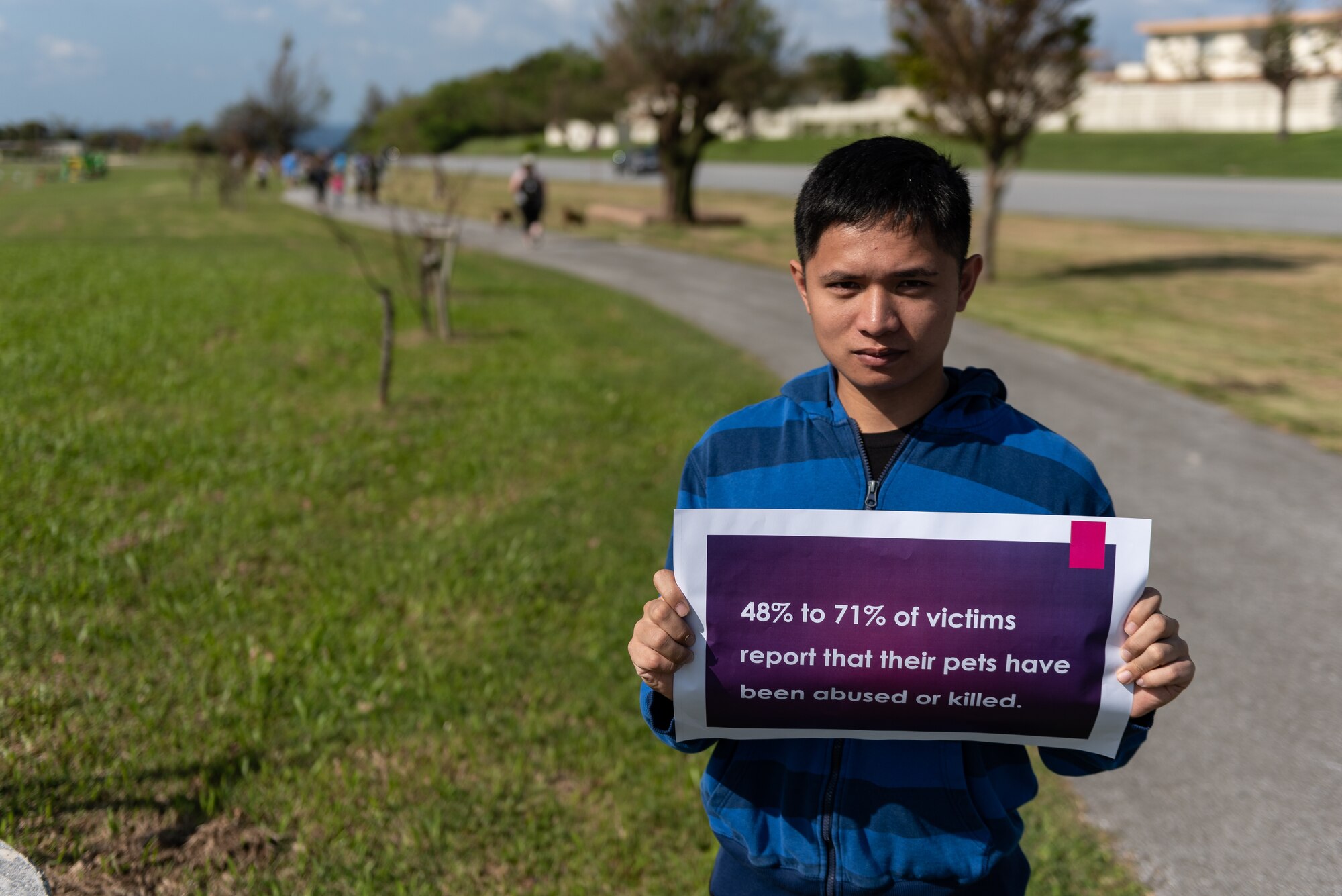U.S. Air Force Senior Airman Jeaftmyr Del Rosario, 18th Component Maintenance Squadron aircraft electrical and environmental journeyman, holds a sign during the Paws Against Domestic Violence event Oct. 20, 2018, at Kadena Air Base, Japan. U.S. Army, Air Force and Marine Corps family advocacy agencies came together to host the event to raise awareness for domestic violence for the Okinawa military community. (U.S. Air Force photo by Staff Sgt. Micaiah Anthony)