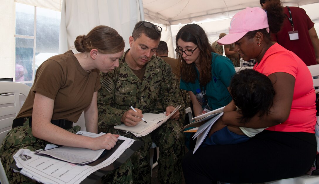 Capt. Gregory Gorman leads members of the pediatrics team in informing a patient about her child’s development.