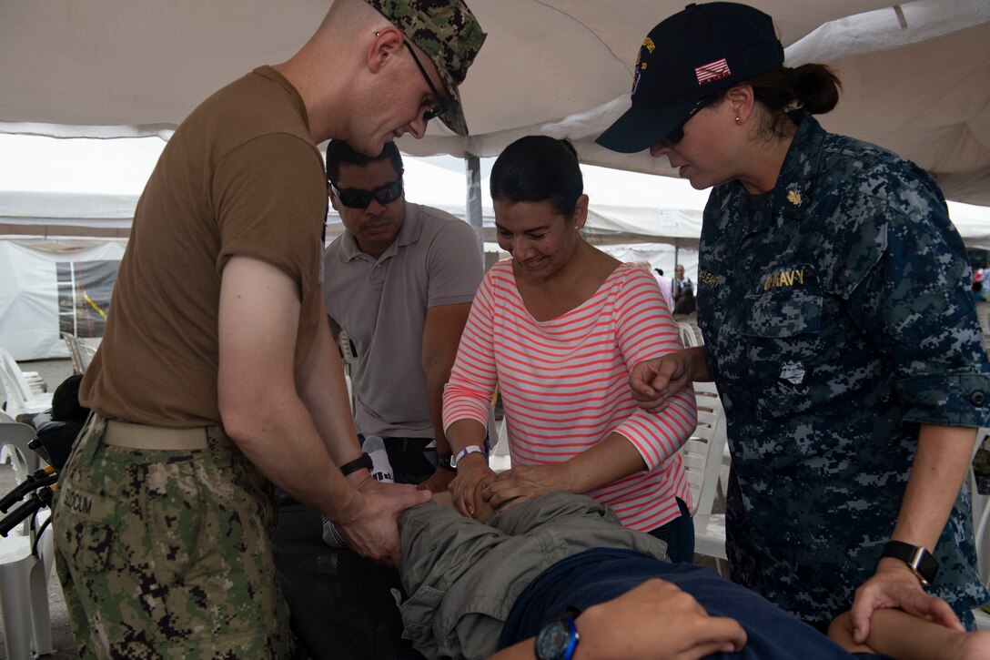 Doctors explain physical therapy techniques to a patient’s mother in Ecuador.