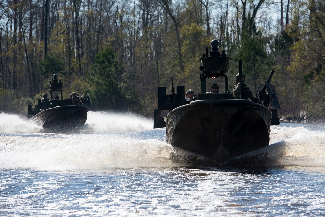 Two military boats operate in the water.