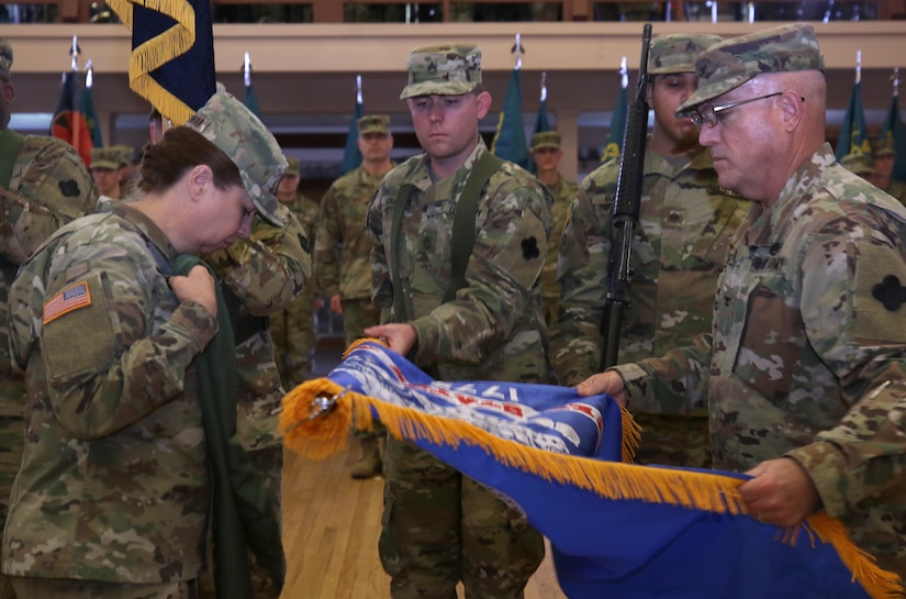 Col. Jeffrey D. Pugh, Mission Command Support Group commanding officer, 88th Readiness Division, unfurls the MCSG colors while Command Sgt. Maj. Sara E. Noskowiak, folds the protective covering during the unit's activation and assumption of command ceremony.