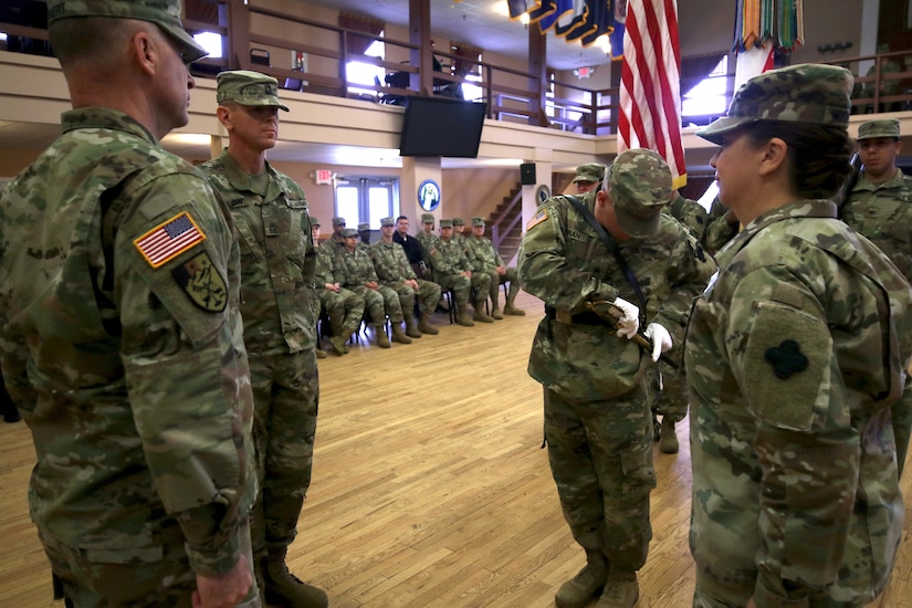 Sgt. Benjamin Moran, 338th Army Band, 88th Readiness Division, sheaths the sword used to pass responsibility for U.S. Army Reserve Bands from Command Sgt. Maj. Sara E. Noskowiak to Master Sgt. Keith M. Barlow during a change of responsibility ceremony at Fort McCoy, Wisconsin, Oct. 20, 2018. Noskowiak owns the 1840 U.S. noncommissioned officer musicians sword. She displays it on a stand, made by her father, with four of her favorite U.S. Army challenge coins.