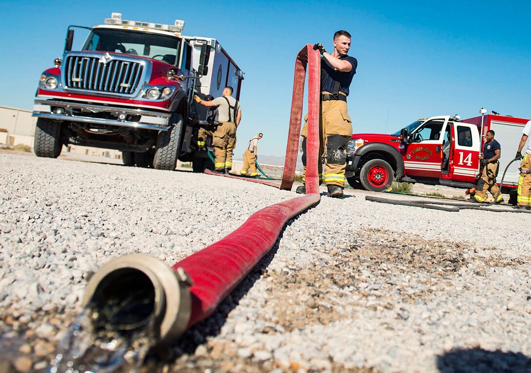 Staff Sgt. Edward Wooten, 99th Civil Engineer Squadron firefighter, prepares to roll up a fire hose at the fire department training area on Nellis Air Force Base, Nev., Oct 24, 2018. Primarily Nellis/Creech fire departments participate in the annual training together, but local fire departments from around Las Vegas may also participate. (U.S. Air Force photo by Airman 1st Class Bryan T. Guthrie)