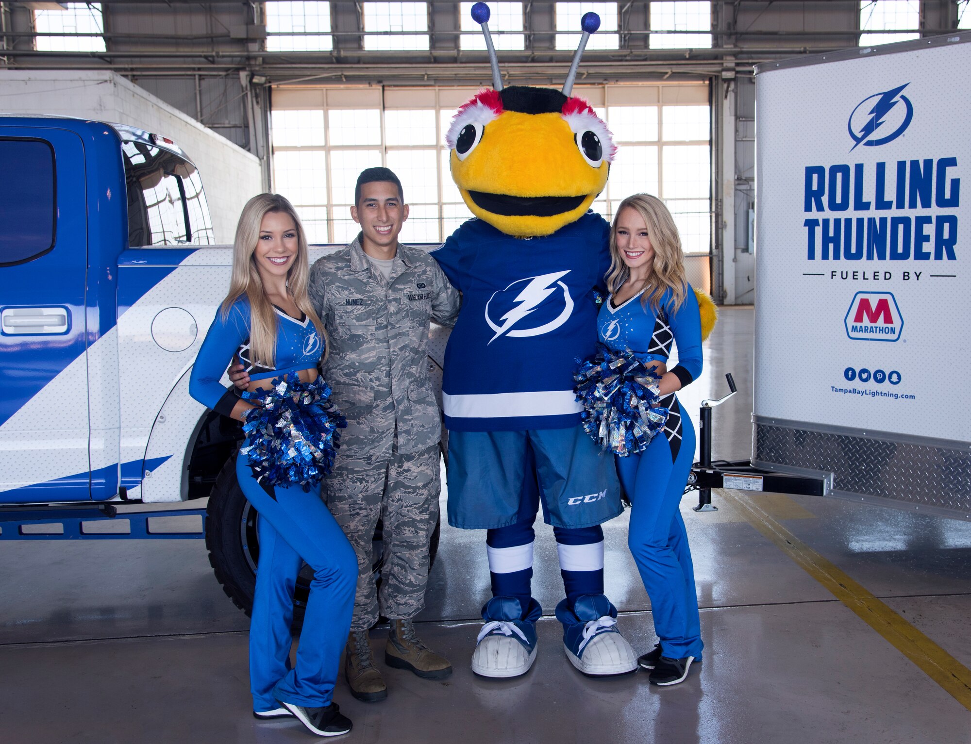 U.S. Air Force Airman 1st Class Caleb Nunez, a photojournalist assigned to the 6th Air Mobility Wing, poses for a photo with the Tampa Bay Lightning girls and team mascot at MacDill Air Force Base, Florida, Oct. 25, 2018.