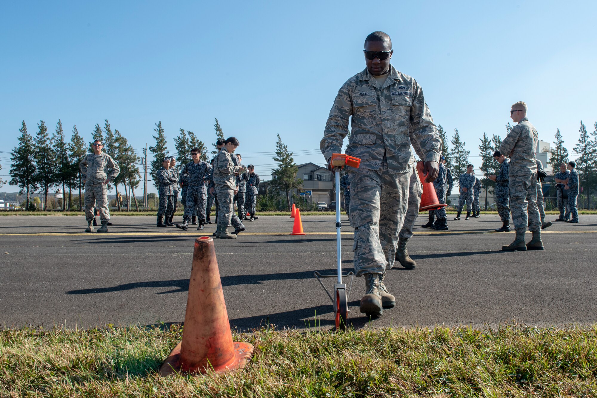 U.S. Air Force Tech. Sgt. Romain Smith, 374th Civil Engineer Squadron electrical power production, measures the width of the runway prior to installing the Mobile Aircraft Arresting System (MAAS) with the help of the Koku Jietai (Japan Air Self-Defense Force) as part of bilateral training at Yokota Air Base, Japan, Oct. 25, 2018.