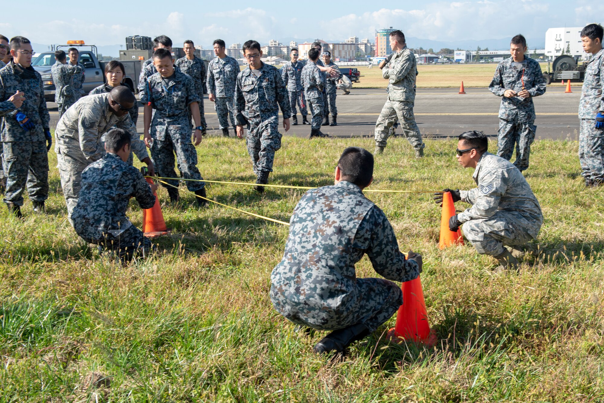 Airmen from the 374th Civil Engineer Squadron work with Koku Jietai (Japan Air Self-Defense Force) members to measure out the proper positioning for the Mobile Aircraft Arresting System (MAAS) at a bilateral training event at Yokota Air Base, Japan, Oct. 25, 2018.