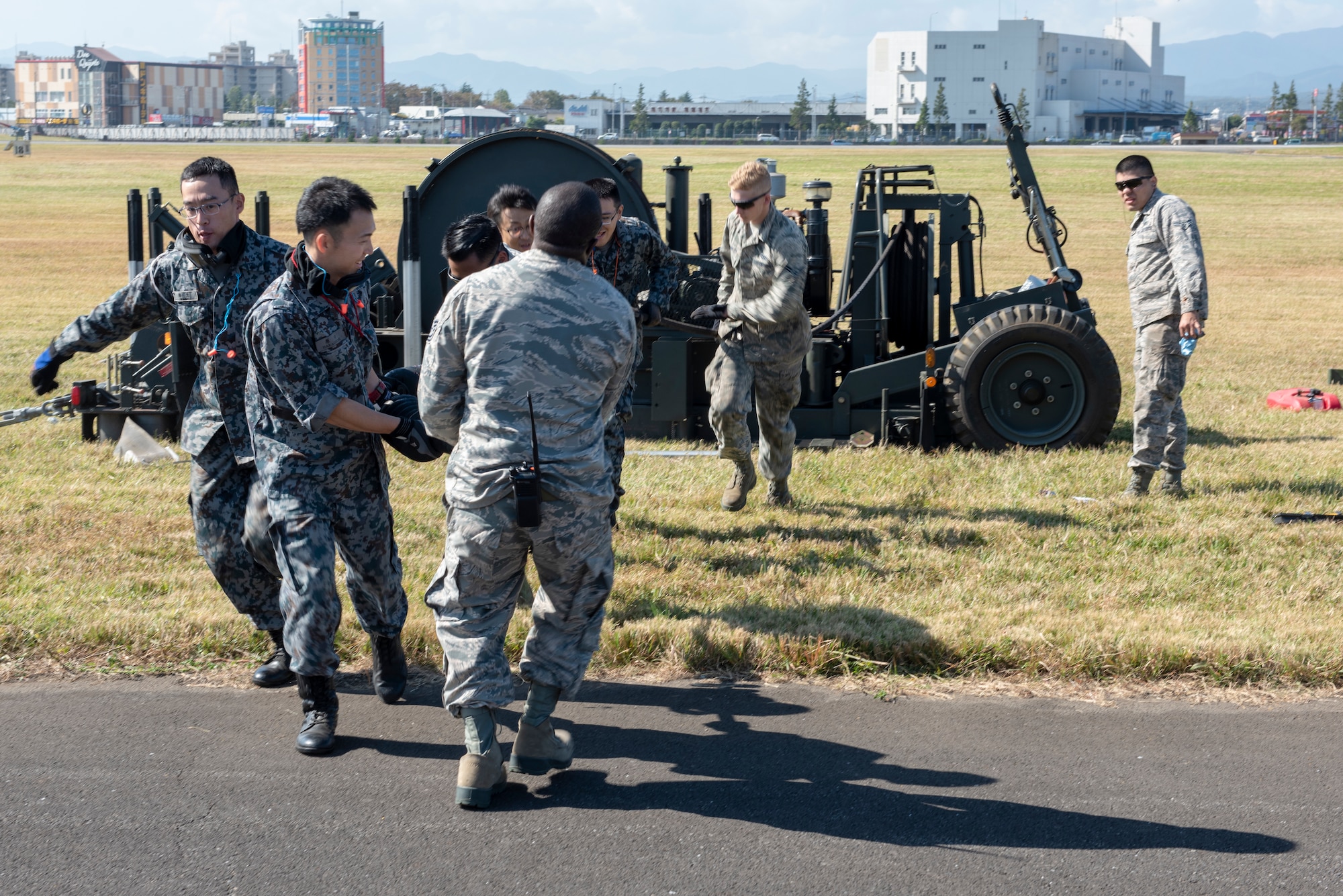 Airmen from the 374th Civil Engineer Squadron work with Koku Jietai (Japan Air Self-Defense Force) members to pull the cable of the Mobile Aircraft Arresting System (MAAS) across the runway at a bilateral training event at Yokota Air Base, Japan, Oct. 25, 2018.