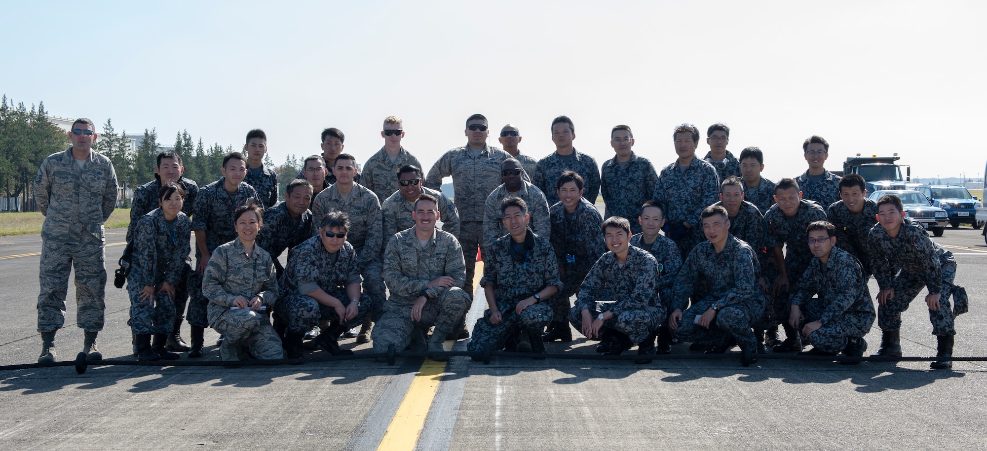 Airmen from the 374th Civil Engineer Squadron and service members from the Koku Jietai (Japan Air Self-Defense Force) pose for a group photo at the completion of the Mobile Aircraft Arresting System (MAAS) at a bilateral training event at Yokota Air Base, Japan, Oct. 25, 2018.
